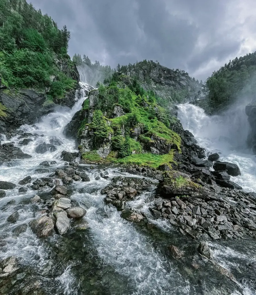 Norveç'te kayalık ve yemyeşil bir vadiden akan görkemli bir dağ şelalesi