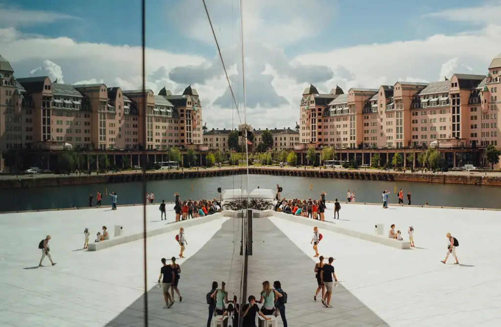 Çatı katındaki meydanda yürüyen ziyaretçilerin bulunduğu, Oslo Modern Opera Binası'nın sahil mimarisi