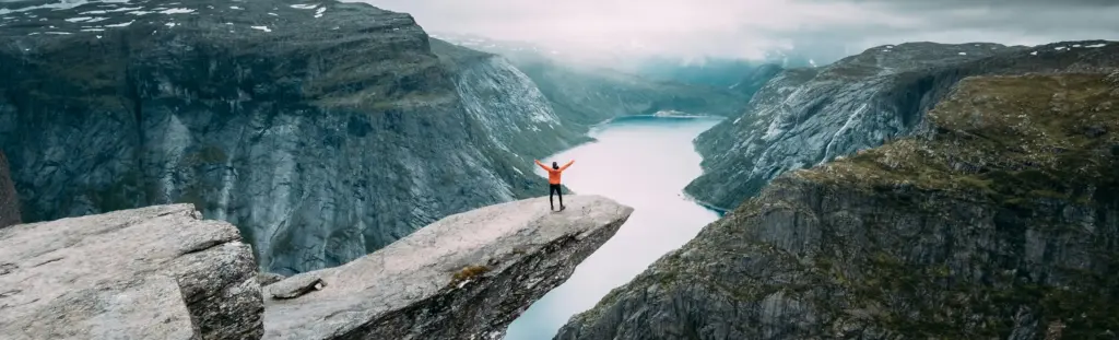 Norveç'te, Trolltunga kayalığının üzerinde duran bir gezgin, nefes kesici fiyort manzarasını seyrediyor